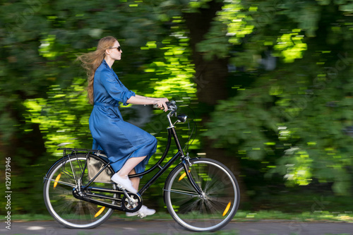 Beautiful young woman and vintage bicycle, summer. Red hair girl riding the old black retro bike outside in the park. Having fun in the city © Artenex
