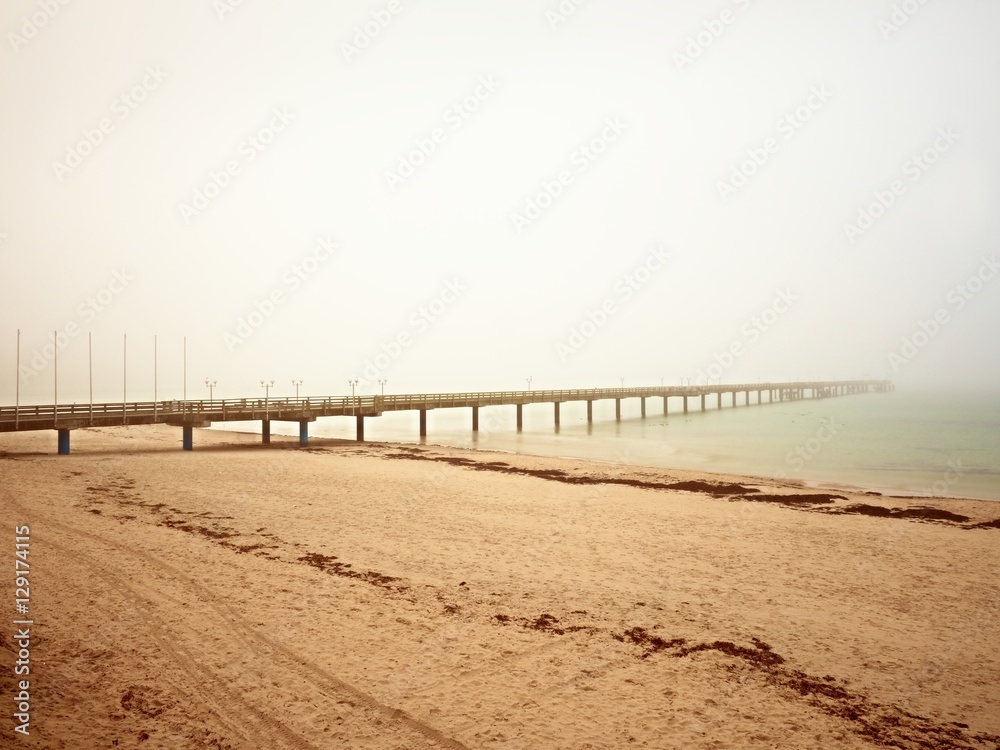 Autumn misty morning on wooden pier above sea. Depression, dark  atmosphere. Touristic mole, wet wooden floor above sea.
