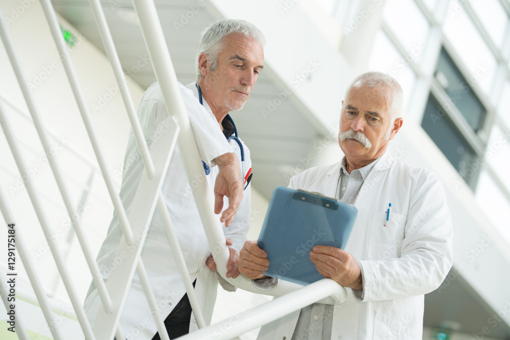 mid section of doctors discussing over clipboard in hospital mid section of doctors discussing over clipboard in hospital
