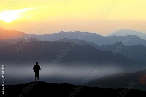 Photos Climber standing the top of mountain in sunset background.