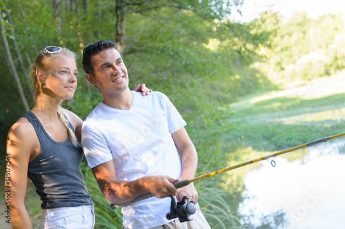 peaceful young couple fishing by the pond