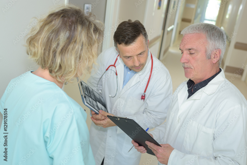 Fototapeta premium two doctors and nurse looking at clipboard in hospital