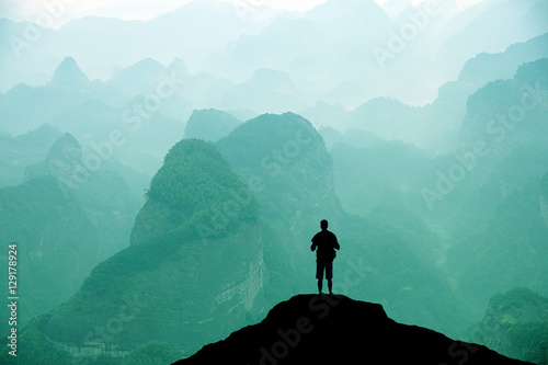 Climber standing the top of mountain in sunset background. 