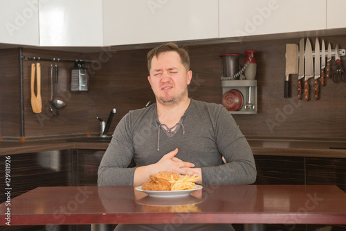Fat man rejecting to eat junk food at home photo