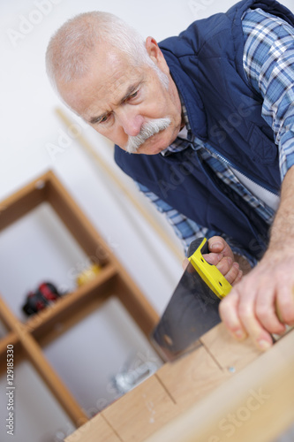 construction worker cutting board with hand saw isolated over white