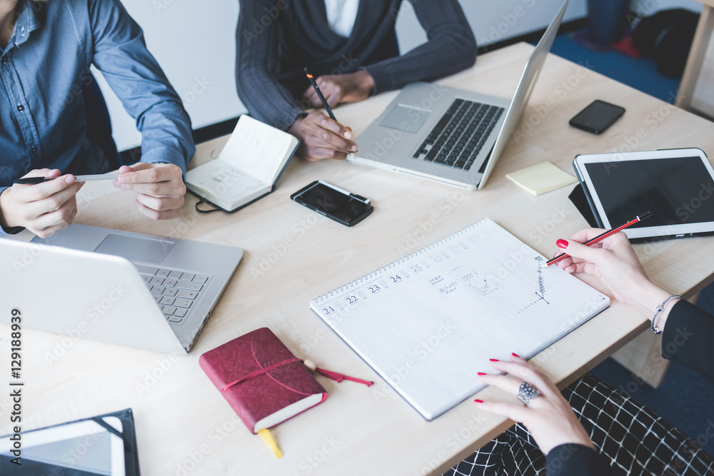 Top view of an office desk with a group of people working using technological devices - work, business, teamwork concept Top view of an office desk with a group of people working using technological devices - work, business, teamwork concept