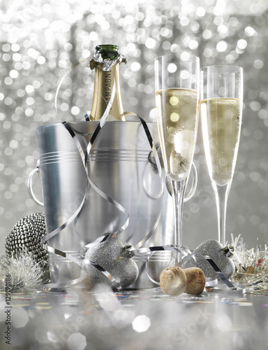 Two glasses of champagne with bottle in cooler on a silver bokeh