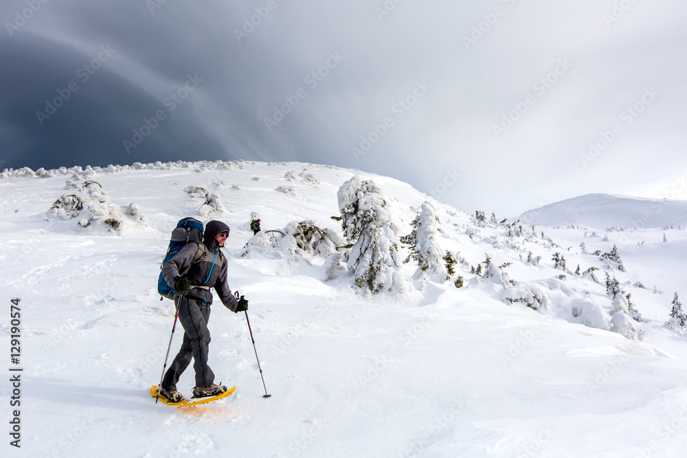 Man hiking in winter mountains before thunderstorm Man hiking in winter mountains before thunderstorm