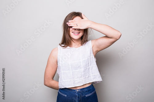 teenager covering her eyes isolated on a gray background