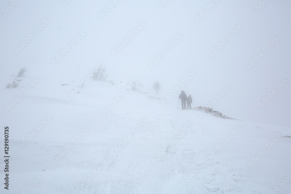 Backpacker walk in strond thunderstorm in winter mountains