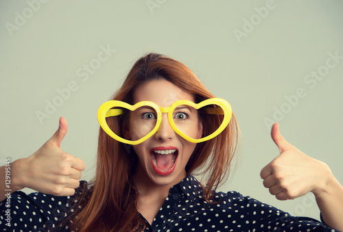 Woman with heart shaped party glasses happy showing thumbs up hands gesture