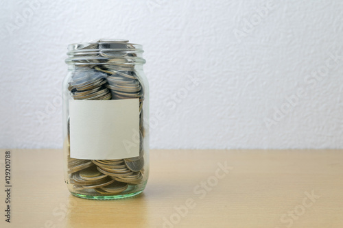 Money jar with coins on wood table