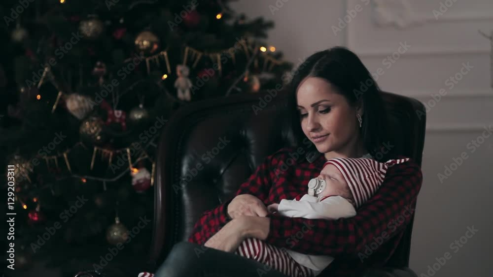 Young mother with a newborn baby and daughter near Christmas tree Young mother with a newborn baby and daughter near Christmas tree
