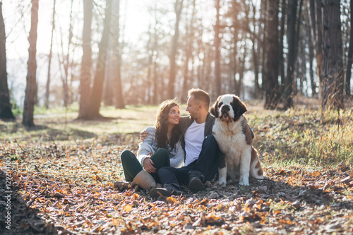 Photography Young couple enjoying nature outdoors together with their Saint Bernard puppy