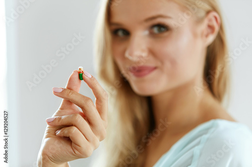 Vitamins And Food Supplements. Beautiful Woman With Pill In Hand