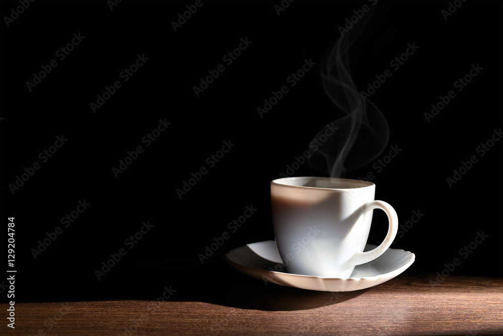 White cup of hot coffee on the table and a dark background White cup of hot coffee on the table and a dark background
