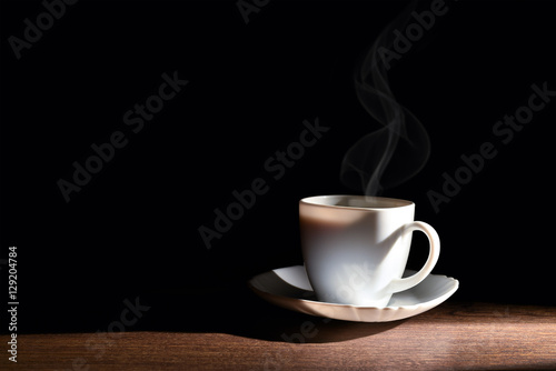 White cup of hot coffee on the table and a dark background