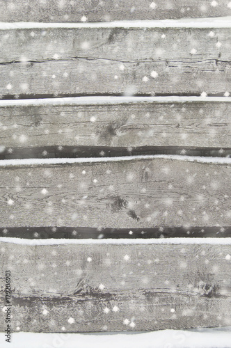 old dark wooden fence in snow. wood background with snowflakes.