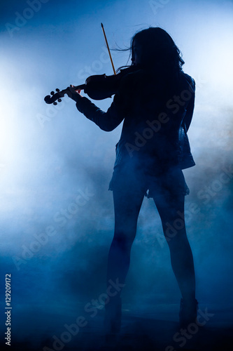 Silhouette of a Rock Woman with Leather Jacket Playing a Violin photo