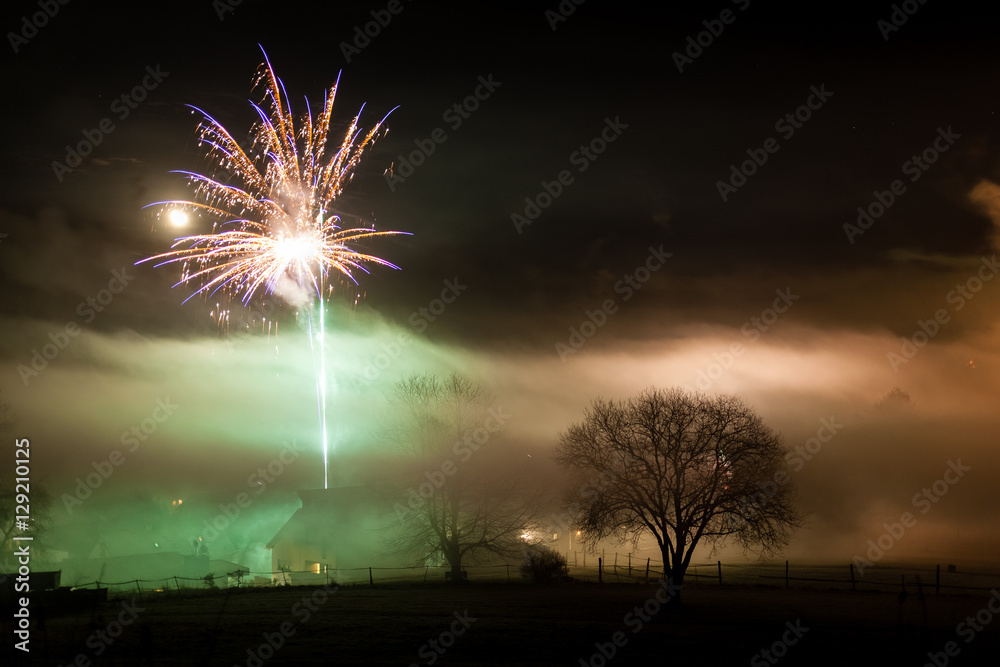 Fireworks over misty village and tree