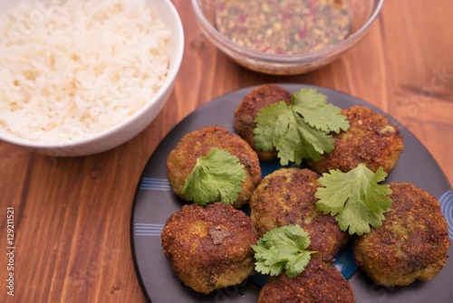 Asian, thai or vietnam style fish and vegetable burgers or fritters with fresh coriander leaves served with boiled rice and homemade fresh sweet chili sauce consist from chili, cucumber, soy sauce.