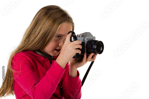 Young girl looking through the viewfinder of a vintage SLR camera isolated on a white background © Steven