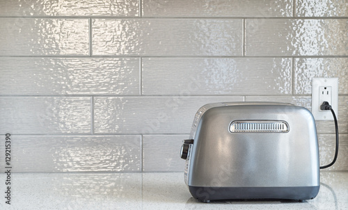 Plugged in retro styled toaster with sliced bread against cerami