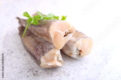 raw fish hake in white packaging decorated with parsley