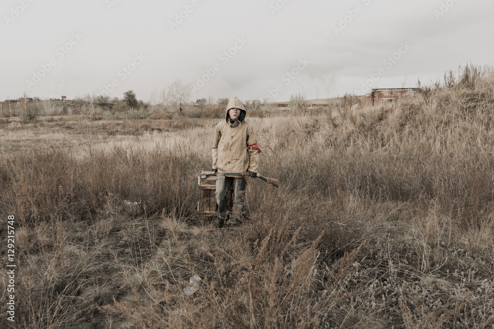 boy carries a wooden box. The boy found the artifact. wanderer in the world of the apocalypse. boy in a protective cloak and hood.  a child soldier. young boy soldier. abandoned military base