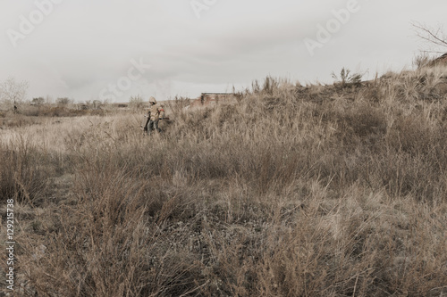 Fototapeta Naklejka Na Ścianę i Meble -  boy carries a wooden box. The boy found the artifact. wanderer in the world of the apocalypse. boy in a protective cloak and hood.  a child soldier. young boy soldier. abandoned military base