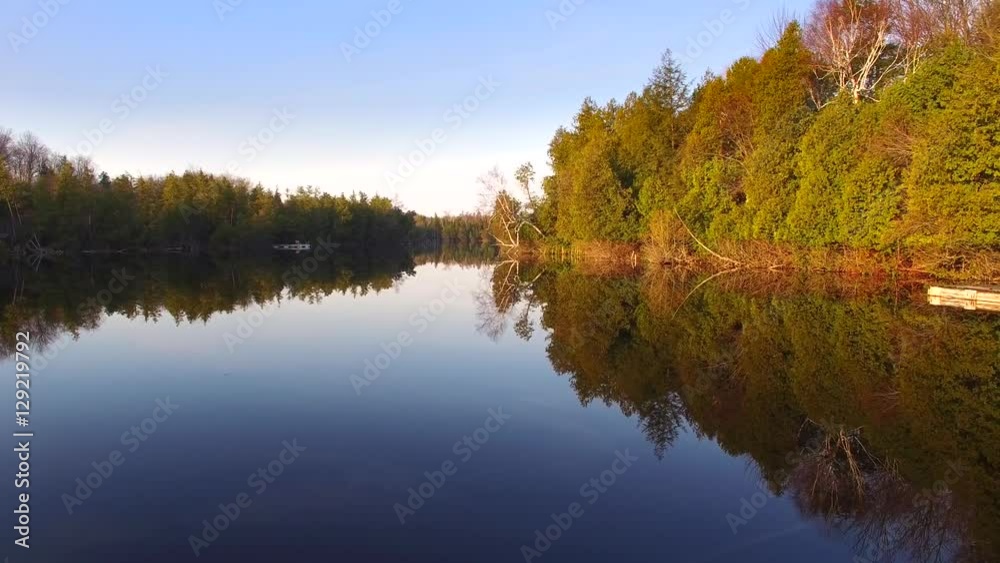 Gliding over mirror-smooth wilderness lake at daybreak, with reflections as perfect as the woodland reality they mimic. Gliding over mirror-smooth wilderness lake at daybreak, with reflections as perfect as the woodland reality they mimic.