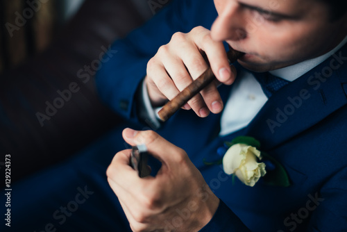 the groom in a suit smoking cigar