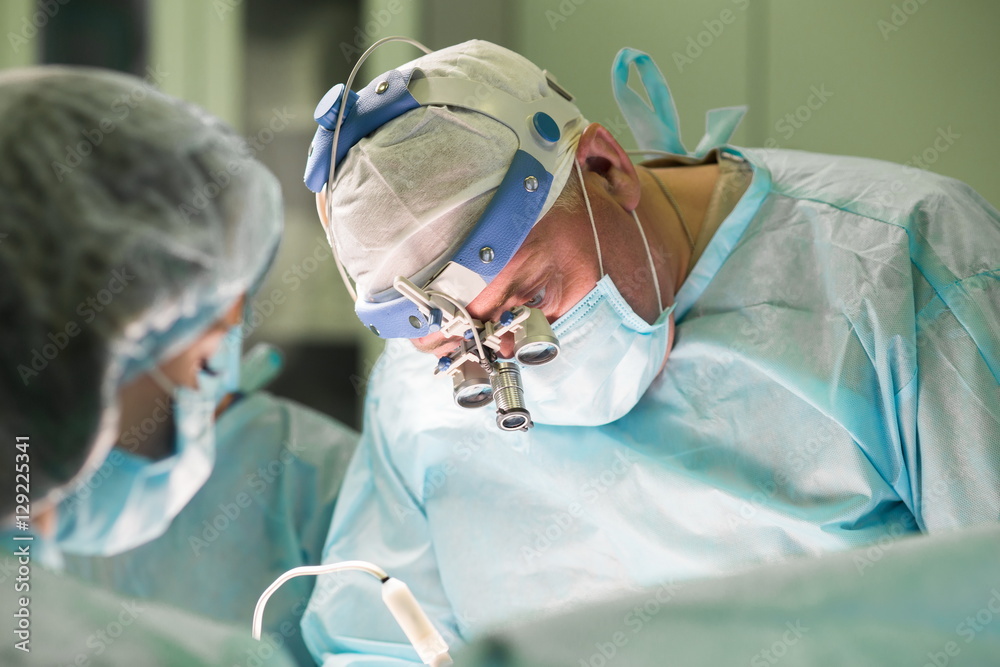 Surgeon and his assistant performing cosmetic surgery in hospital