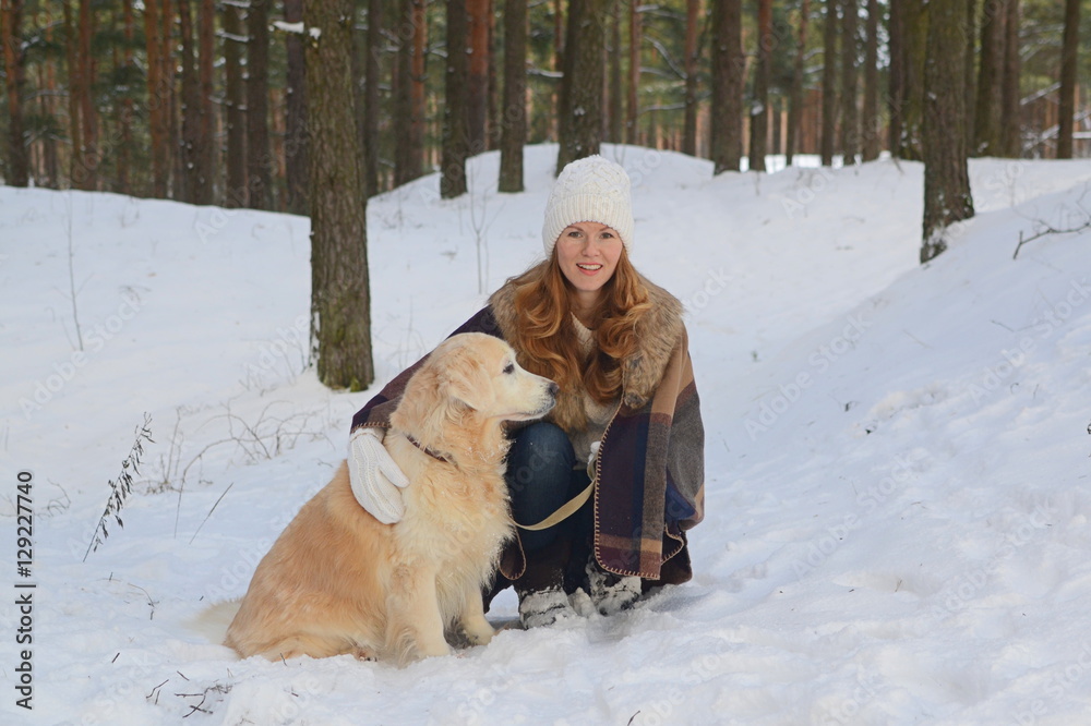 Pretty young woman in winter forest walking with her dog