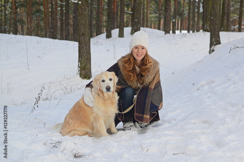 Pretty young woman in winter forest walking with her dog