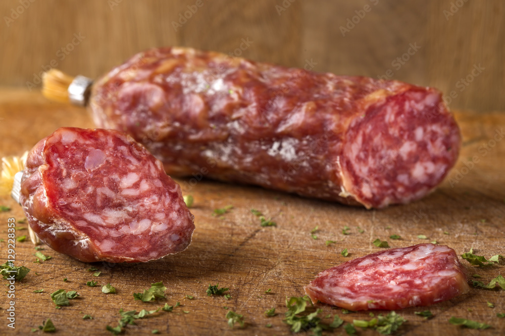 Italian salami on wooden cutting board with herbs Italian salami on wooden cutting board with herbs