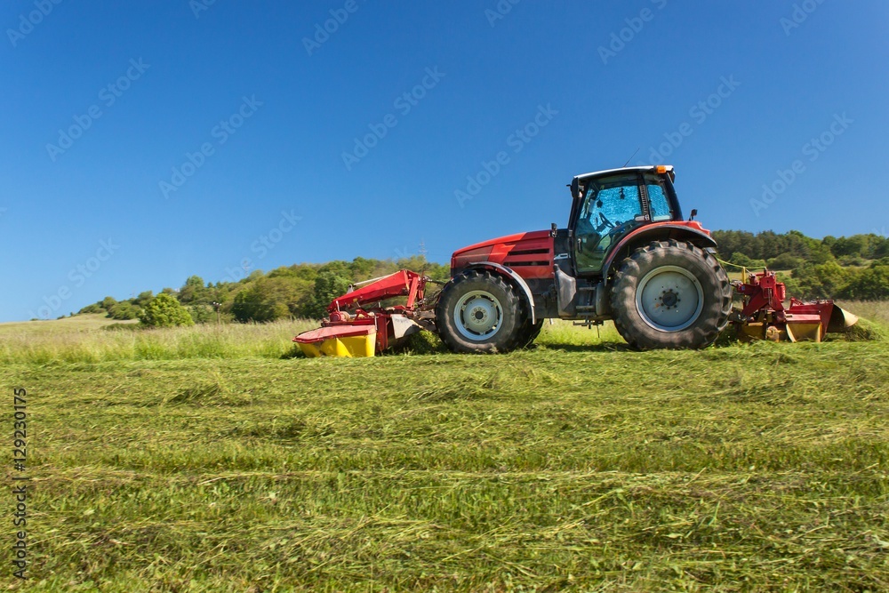 Agricultural work. Red tractor mowing the meadow, Czech Republic. Farmer harvested hay.
Agricultural work. Red tractor mowing the meadow, Czech Republic. Farmer harvested hay.