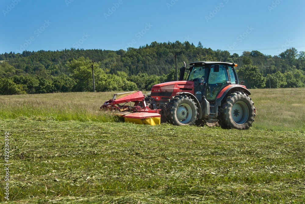 Agricultural work. Red tractor mowing the meadow, Czech Republic. Farmer harvested hay.
Agricultural work. Red tractor mowing the meadow, Czech Republic. Farmer harvested hay.