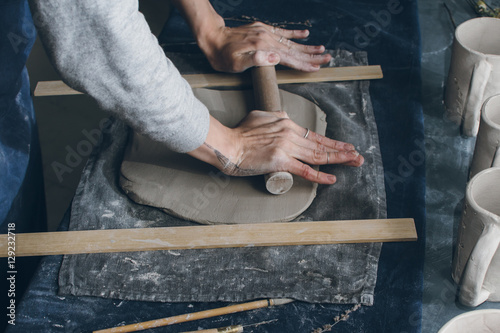 Vászonkép Person using rolling pin to flatten clay