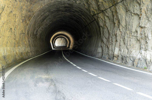 Tunnel. Stretch of road that goes under a rocky mountain range. Abstract scene. Rings of brightness.