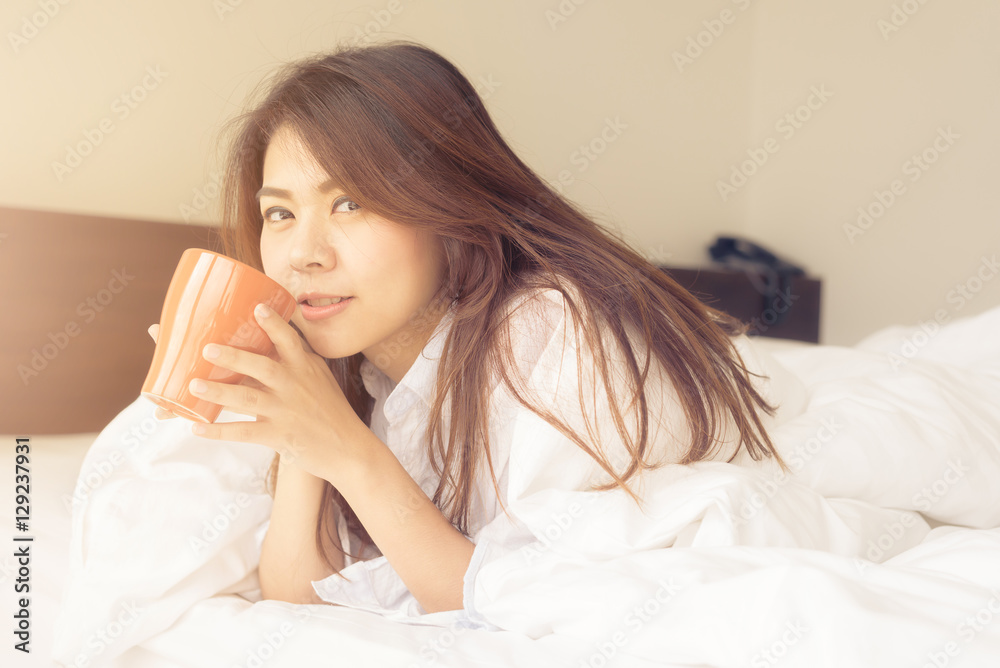 Happy beautiful young Asian woman smile while enjoy drinking coffee in morning in bed room. Happy beautiful young Asian woman smile while enjoy drinking coffee in morning in bed room.