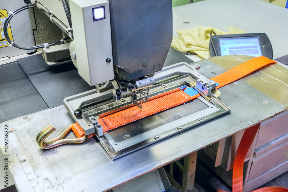 Industrial sewing machine sews a ratchet strap. Industrial sewing machine sews a ratchet strap.