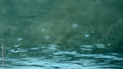 This is a slow motion video of raindrop hitting the ground creating puddles and will work well as a background with pretty green and blue colors