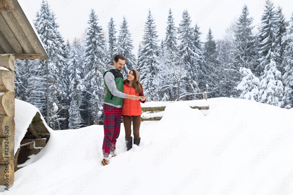 Young Couple Using Smart Phone Snowy Village Wooden Country House Man And Woman Online Messaging Winter Snow Resort Cottage Holiday Vacation