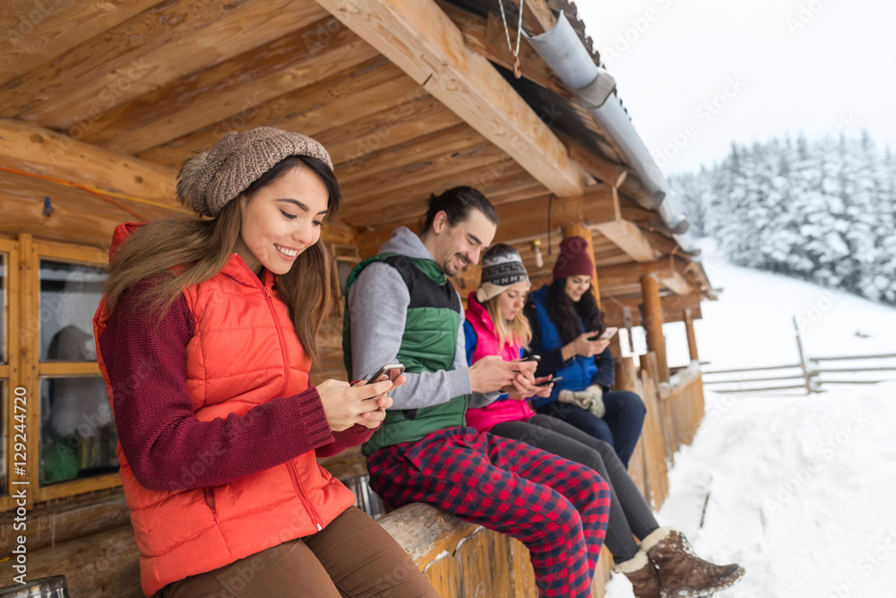 People Group Using Smart Phone Chatting Outdoor Messaging Internet Wooden Country House Winter Snow Resort Cottage Friends On Vacation