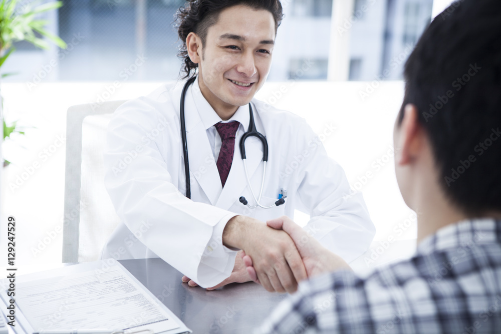 The doctor encourages the patient in the examination room The doctor encourages the patient in the examination room