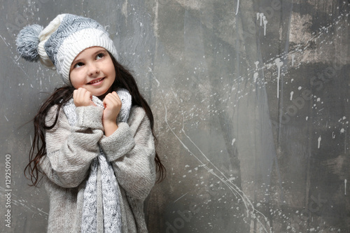 Cute little girl in warm clothes on grunge background