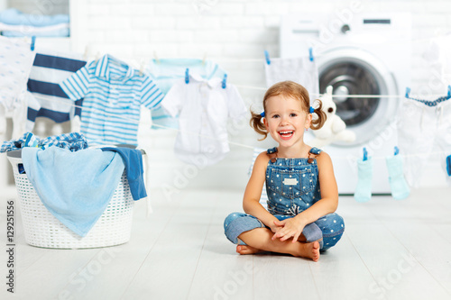 child fun happy little girl  to wash clothes and laughs in laund photo