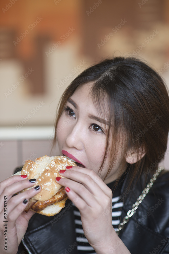Chinese girl is eating hamburgers.