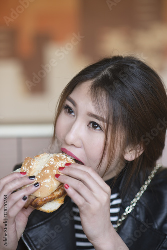 Chinese girl is eating hamburgers.